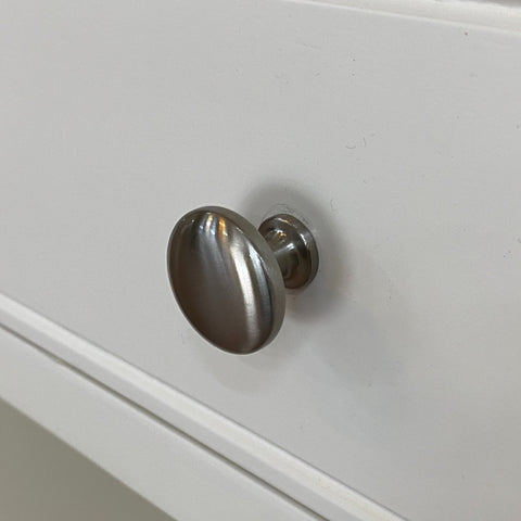 Metallic cabinet knob on a white cabinet door