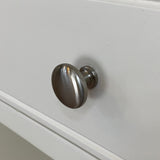 Metallic cabinet knob on a white cabinet door