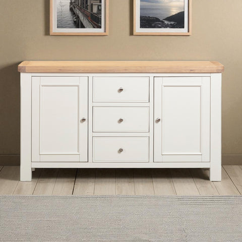 White sideboard with wooden top in a room with framed pictures on the wall.