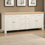 White sideboard with wooden top in a room with framed pictures on the wall.