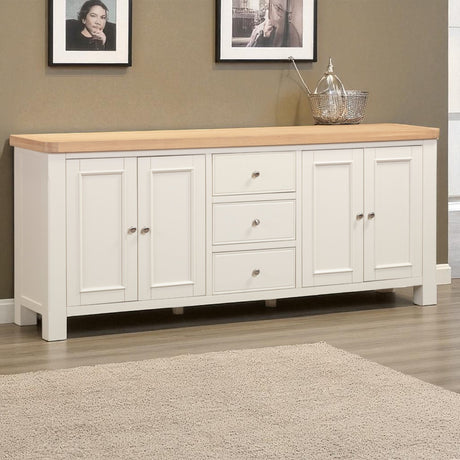 White sideboard with wooden top in a room with framed pictures on the wall.