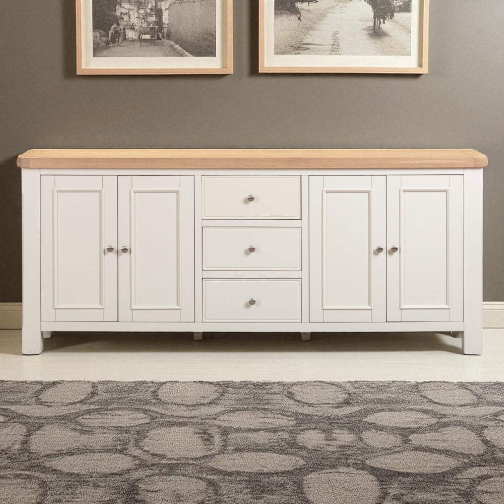 White sideboard with wooden top against a gray wall with framed pictures.
