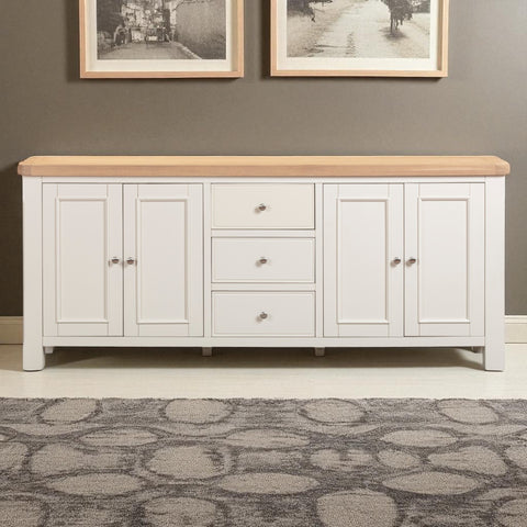 White sideboard with wooden top against a gray wall with framed pictures.