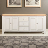 White sideboard with wooden top against a gray wall with framed pictures.
