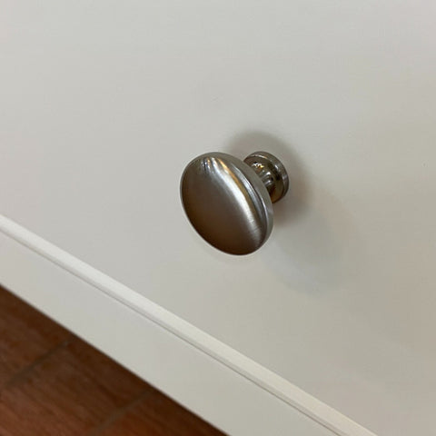 Metallic cabinet knob on a white cabinet door