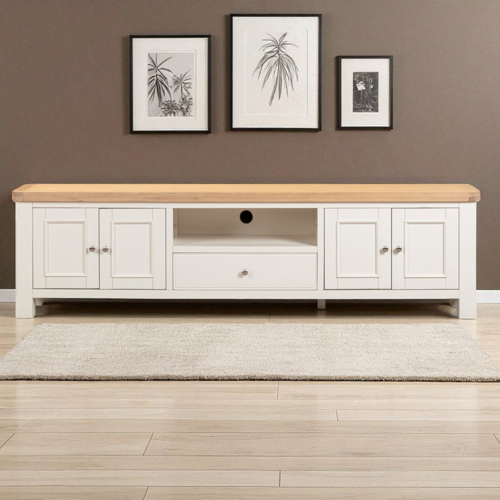 White entertainment console with wooden top against a brown wall with framed pictures.