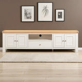 White entertainment console with wooden top against a brown wall with framed pictures.