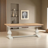 Wooden dining table with white base in a room with shelves and a painting on the wall.