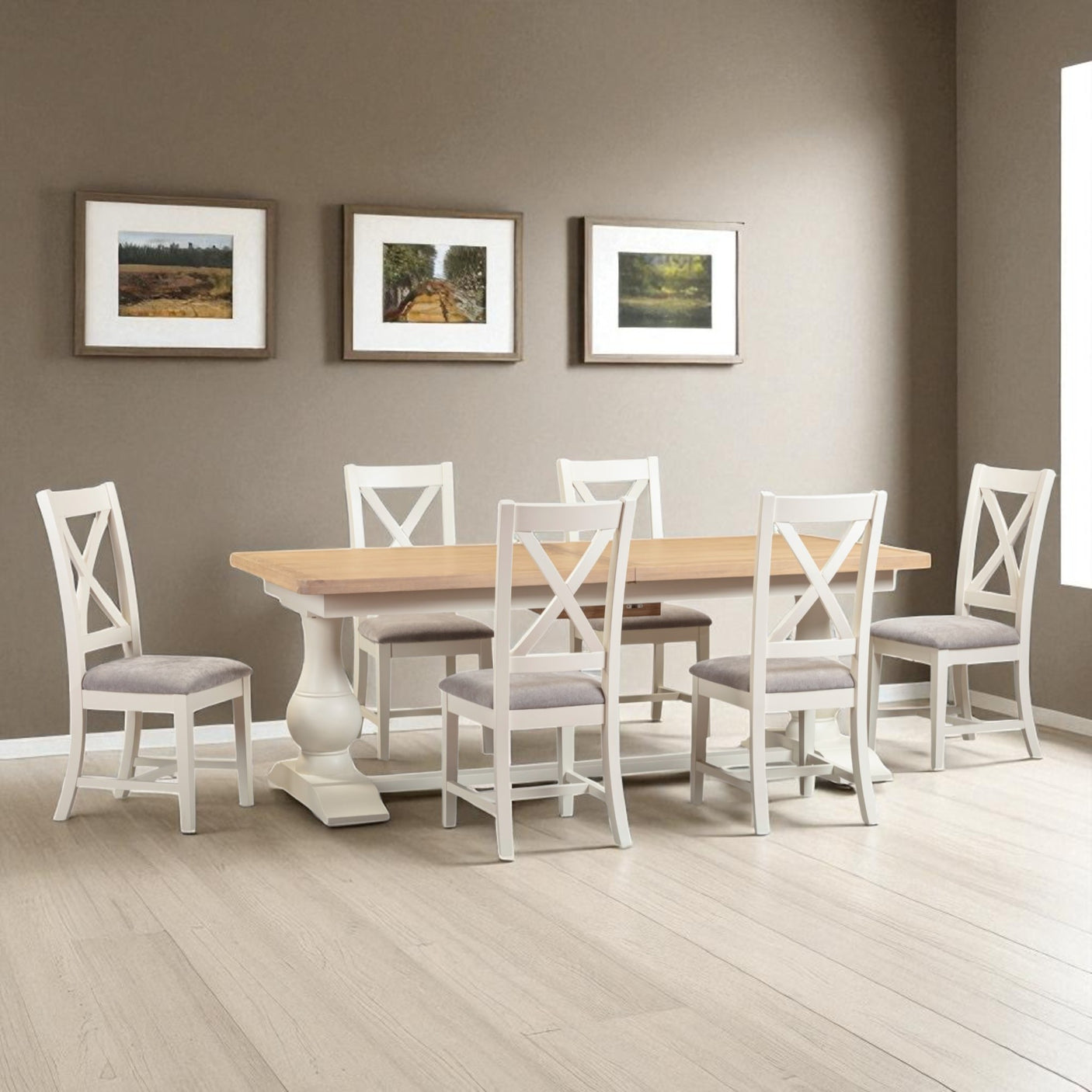 Dining room with a wooden table and white chairs against a gray wall with framed pictures.