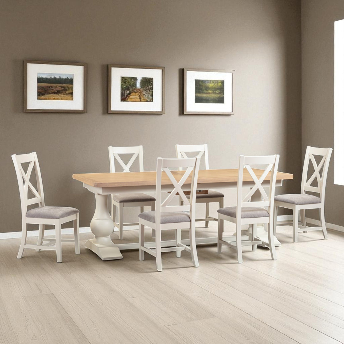 Dining room with a wooden table and white chairs against a gray wall with framed pictures.
