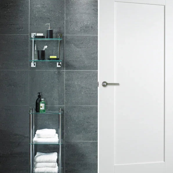 White shaker interior door in modern bathroom with dark tile wall and chrome handle