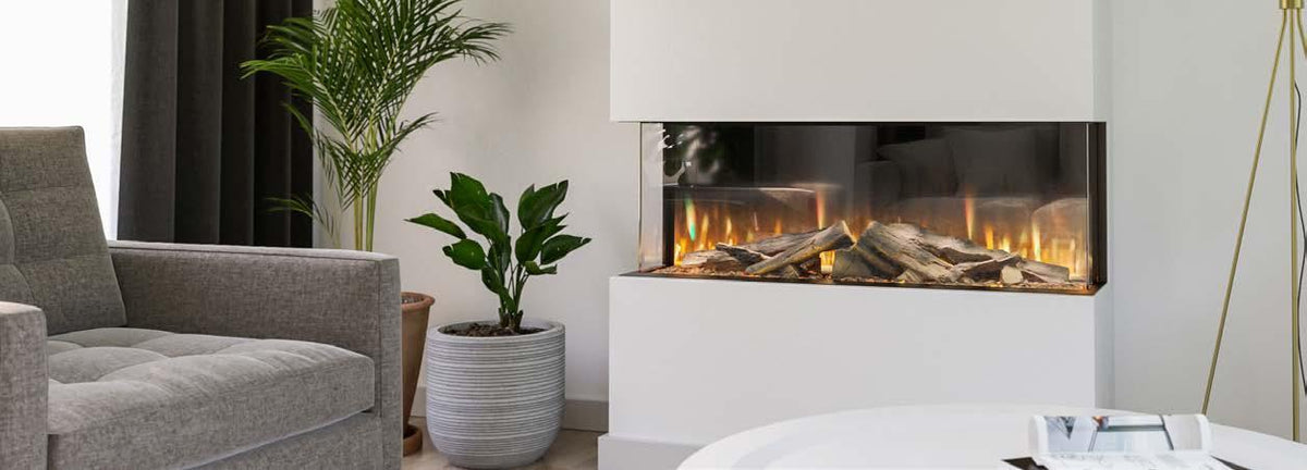Modern electric fireplace with realistic logs and flames beside grey sofa and potted plants