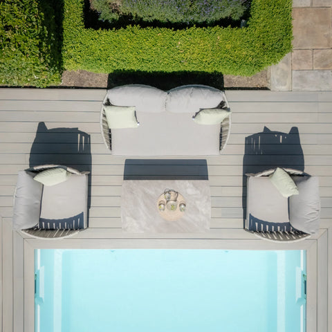 Outdoor garden sofa set with light grey cushions and coffee table beside a pool