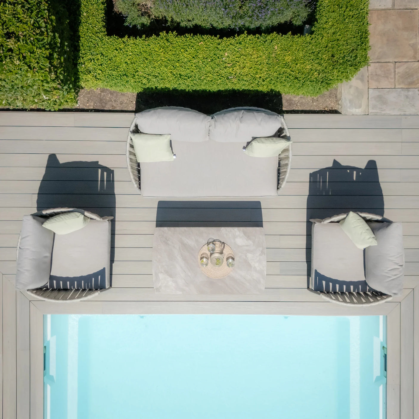 Outdoor garden sofa set with light grey cushions and coffee table beside a pool