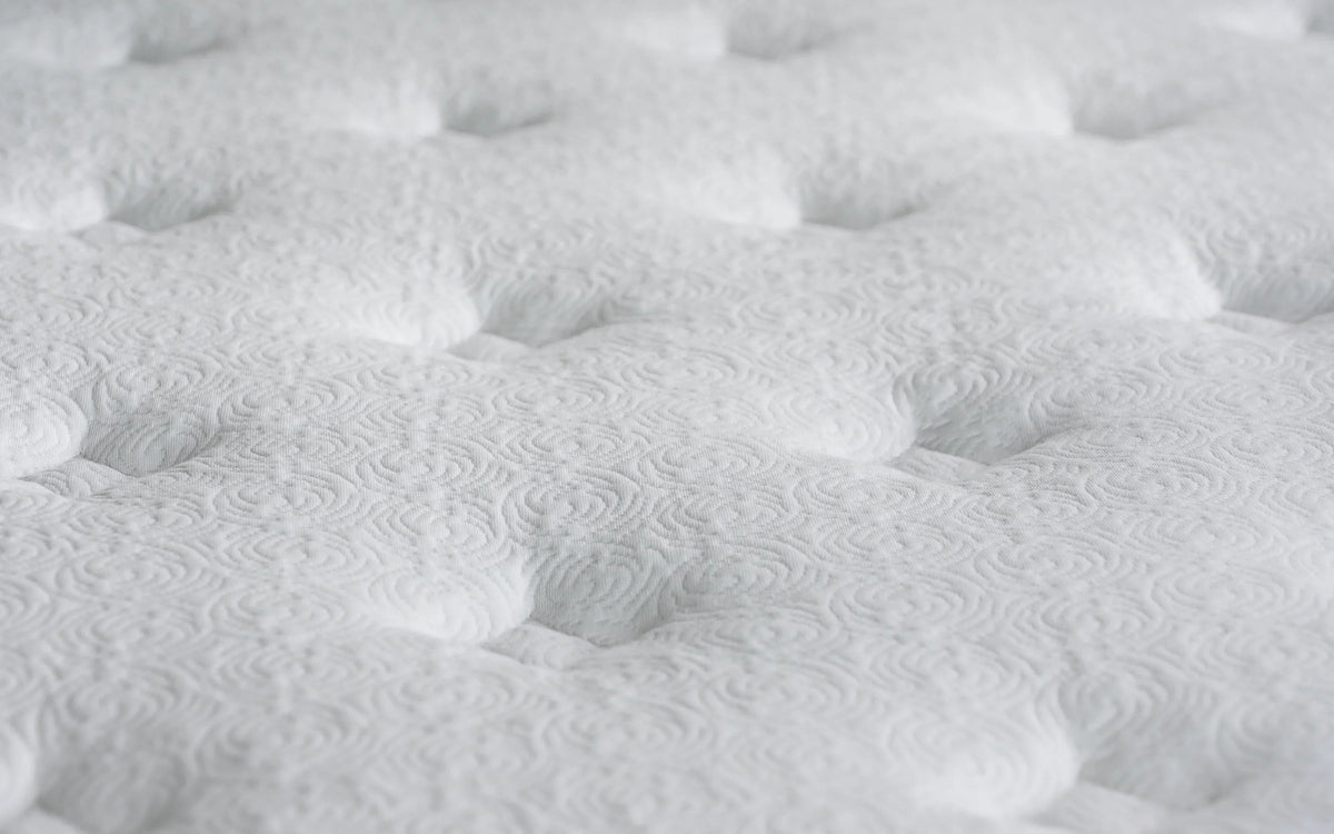 Closeup of white mattress surface with tufted pattern detail