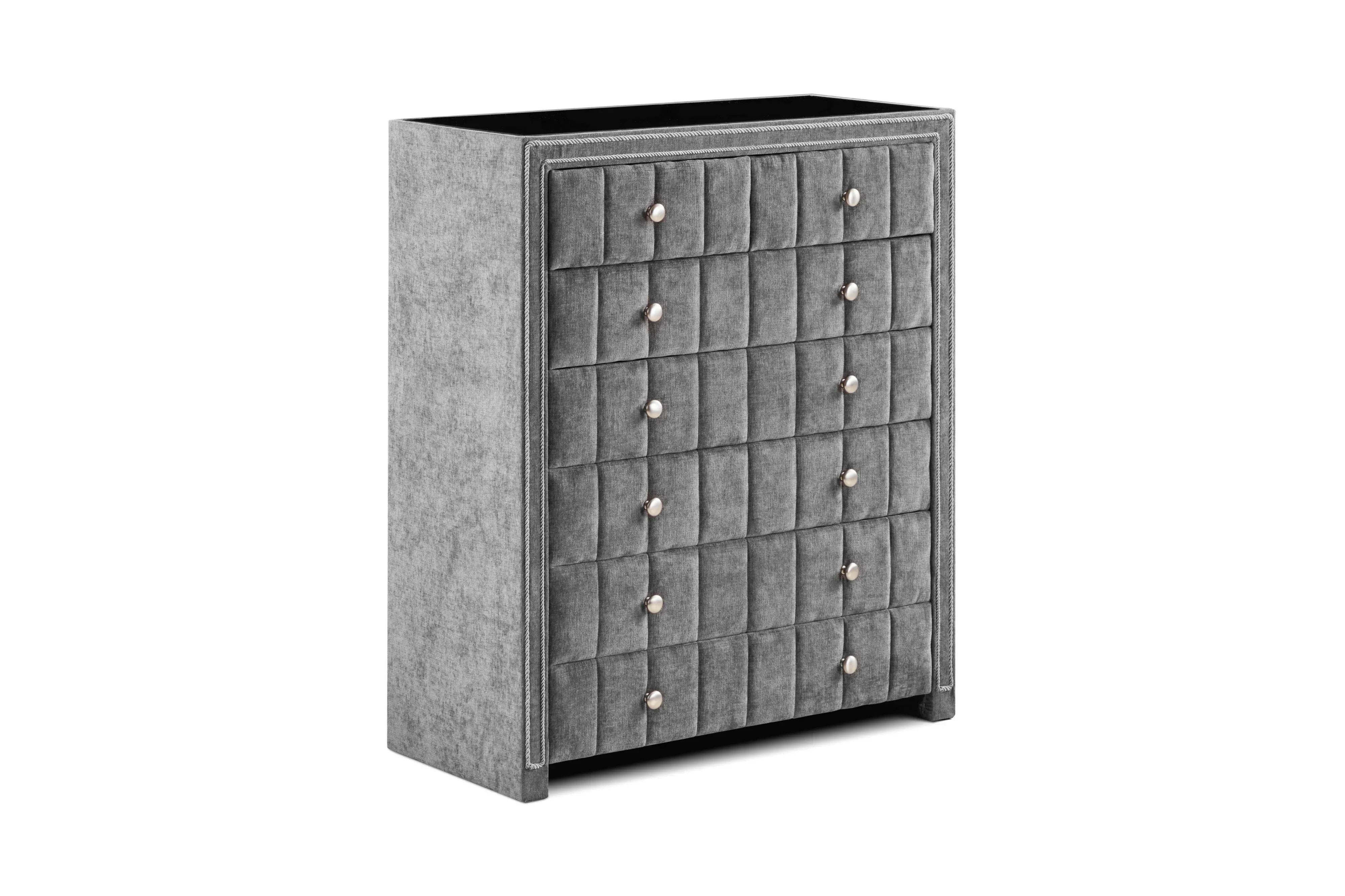 Grey fabric chest of drawers with tufted front and silver knobs, angled view
