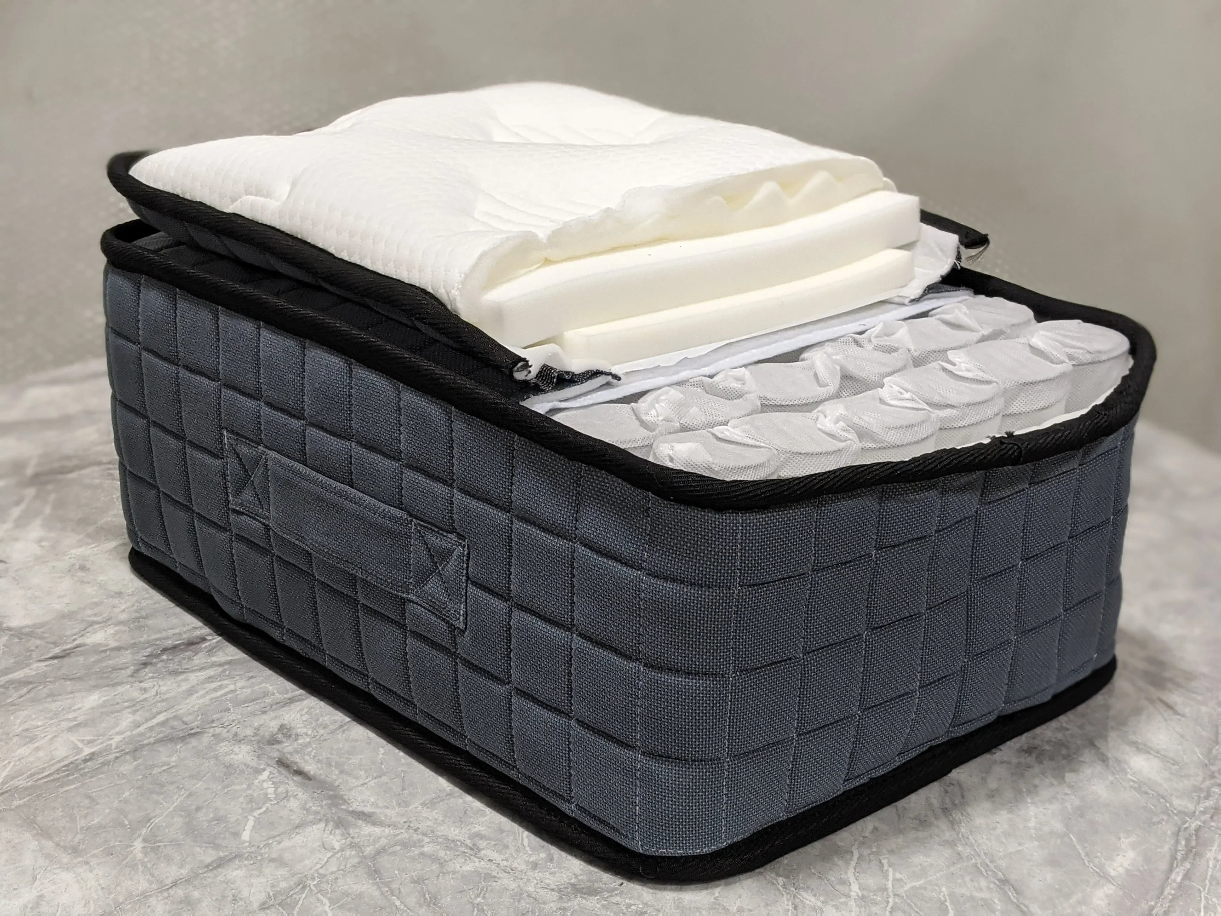 Pocket sprung mattress cross section showing grey quilted fabric and foam layers