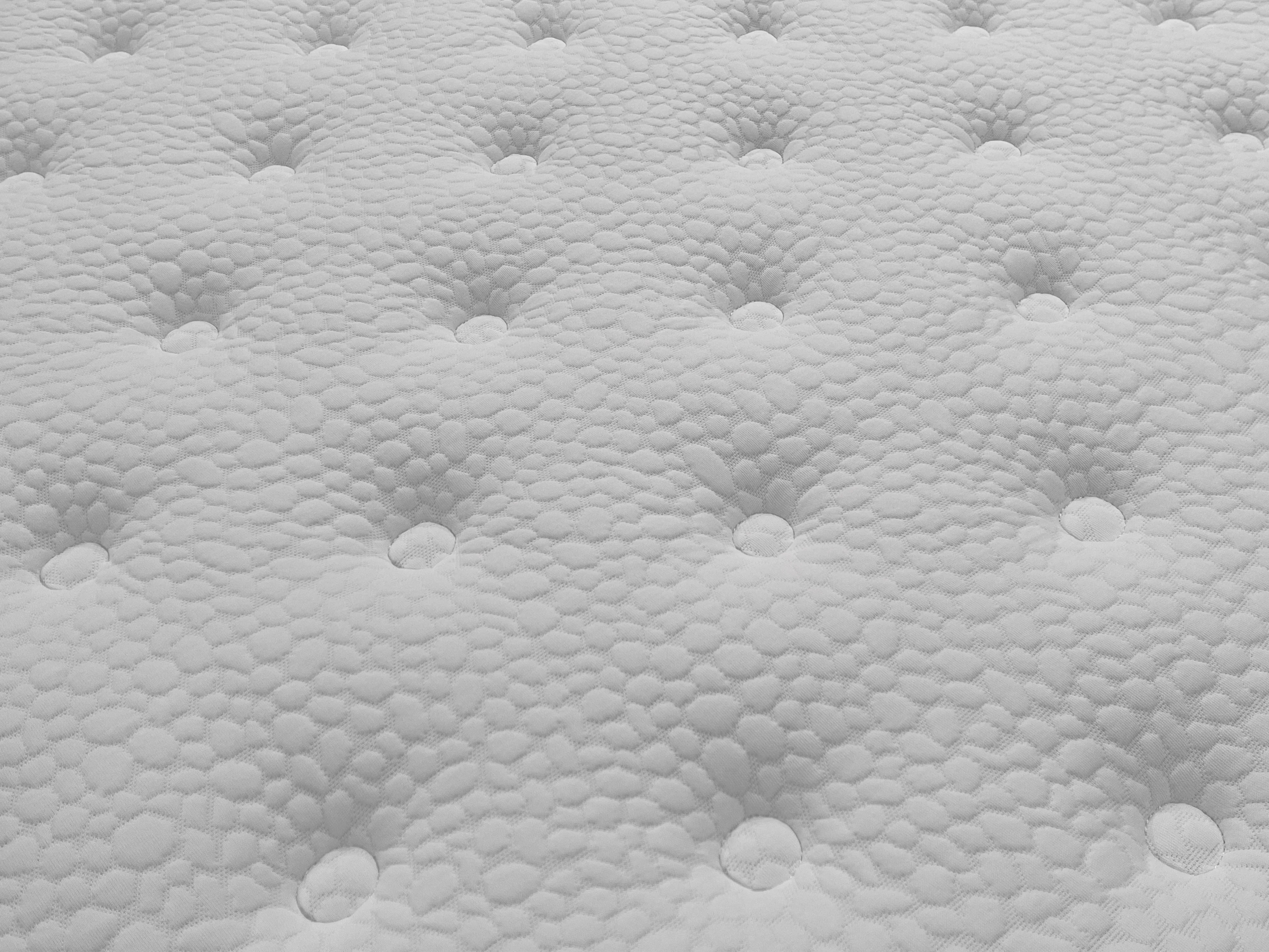 Close up of white mattress surface with tufted button design and textured fabric