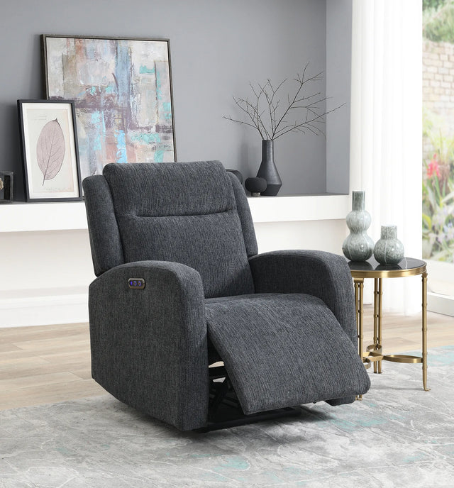 A dark gray upholstered recliner chair shown in a styled living room setting with a side table, framed wall art, and a window.