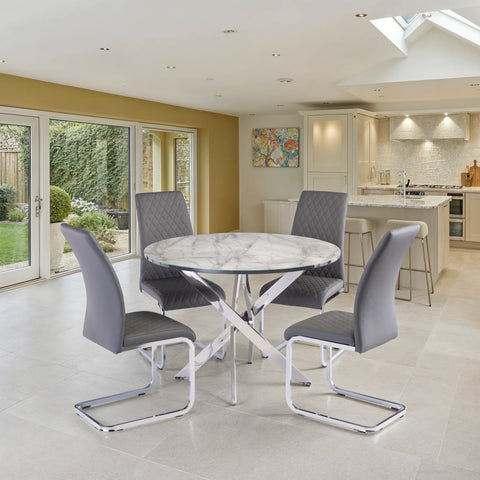 A modern round dining table with a white and gray marble-patterned top and chrome cross base, surrounded by four gray upholstered chairs with chrome cantilever legs, set in a bright contemporary kitchen and dining room.