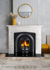 Grey marble fireplace with fire grate, round wall mirror, and yellow vase on mantel