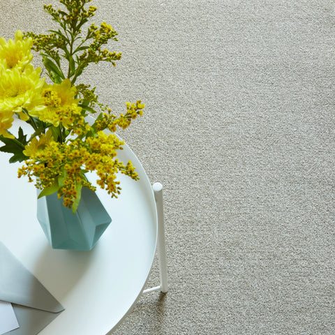Beige carpet flooring with round white coffee table and yellow flower arrangement
