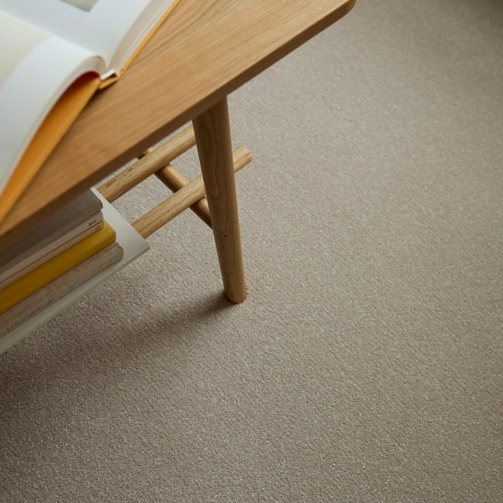 Apollo Plus Sea Breeze carpet in beige under a wooden table with books