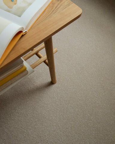 Apollo Plus Sea Breeze carpet in beige under a wooden table with books