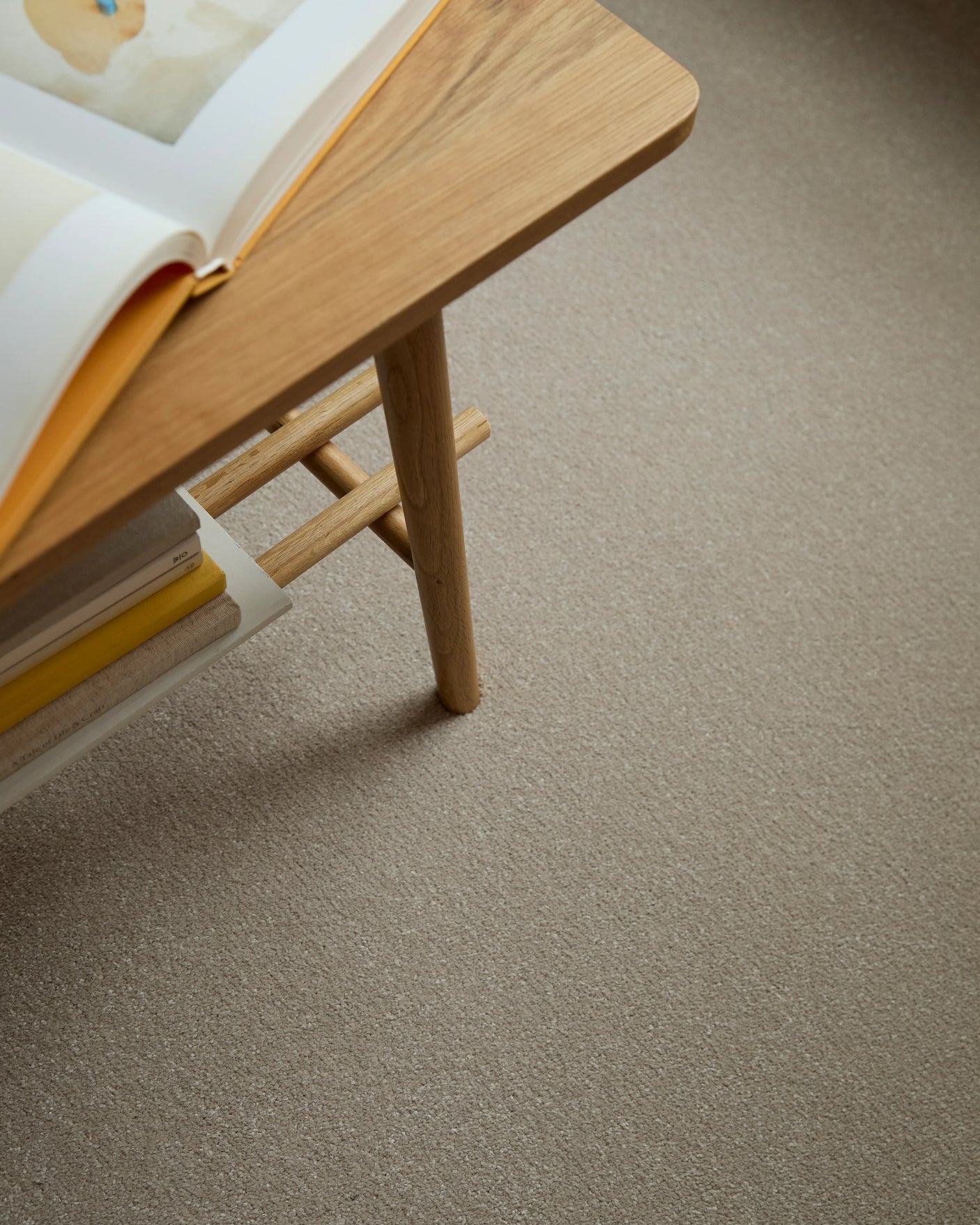 Apollo Plus Sea Breeze carpet in beige under a wooden table with books