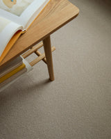Apollo Plus Sea Breeze carpet in beige under a wooden table with books