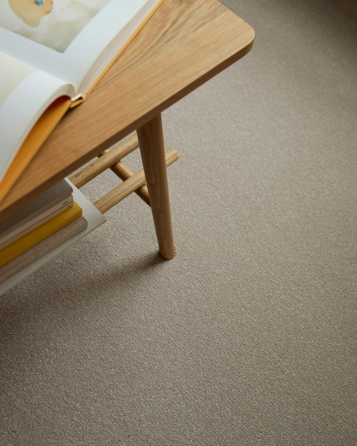 Apollo Plus Sea Breeze carpet in beige under a wooden table with books