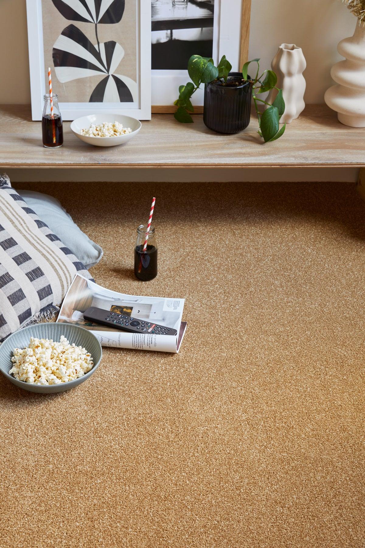 textured beige carpet with cushion, popcorn bowl, remote and drinks in cosy living room setting