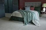 Modern bedroom with upholstered bed, layered bedding, scatter cushions, and grey carpet