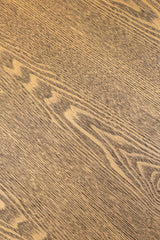 A close-up texture of a medium brown wood grain surface with natural light tan streaks and darker brown lines.