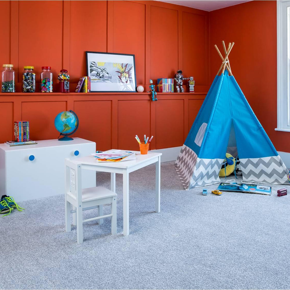 Light grey carpet in modern kids playroom with orange wall, white furniture and blue teepee tent