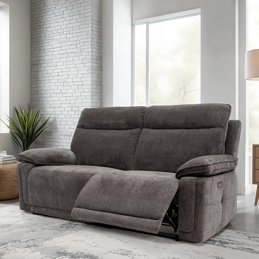 Gray sofa in a living room with large windows and a lamp.