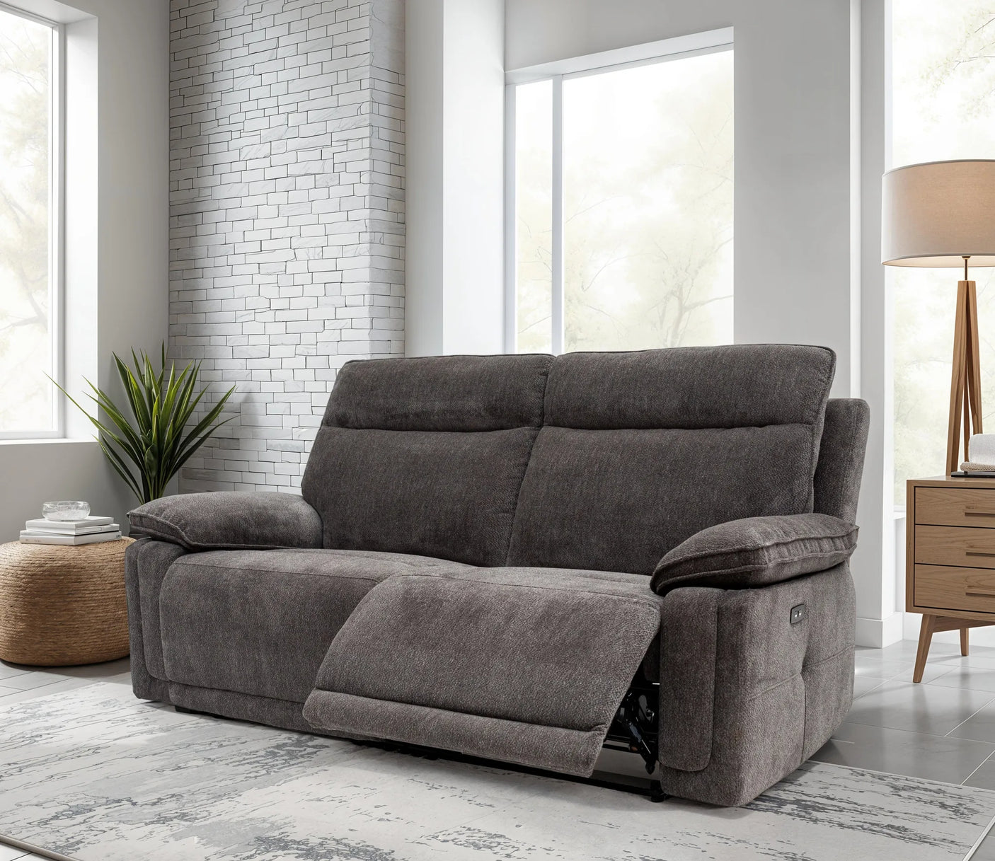 Gray sofa in a living room with large windows and a lamp.