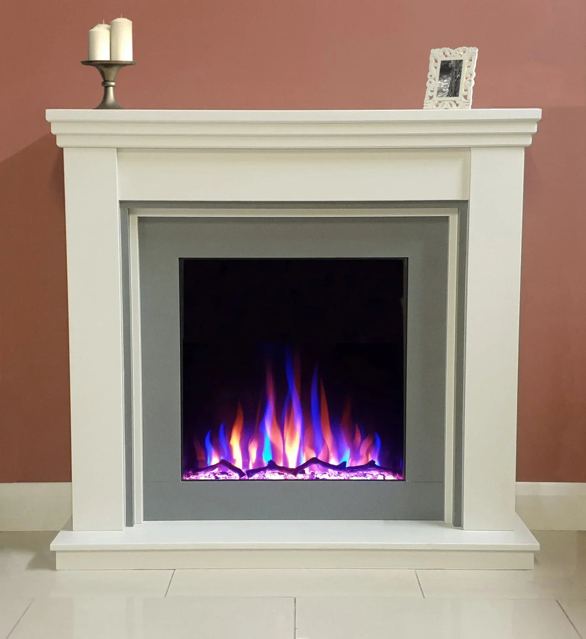 White electric fireplace with glowing multicolour flames and candles on mantel