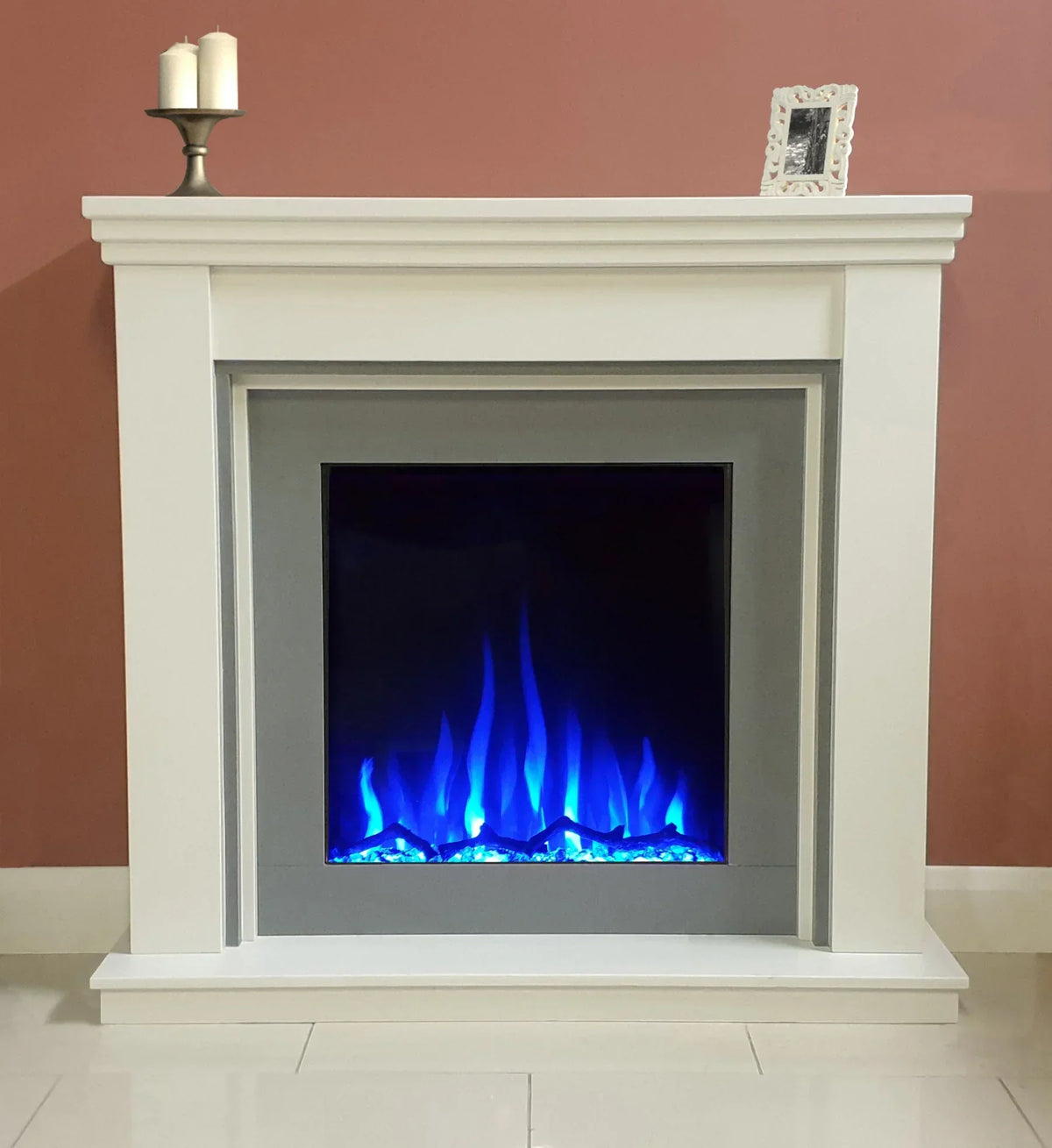 Modern electric fireplace suite with white surround and blue flame effect against pink wall