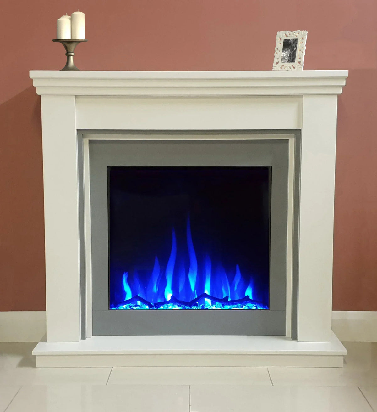 white electric fireplace with blue LED flame and mantel against dusky pink wall