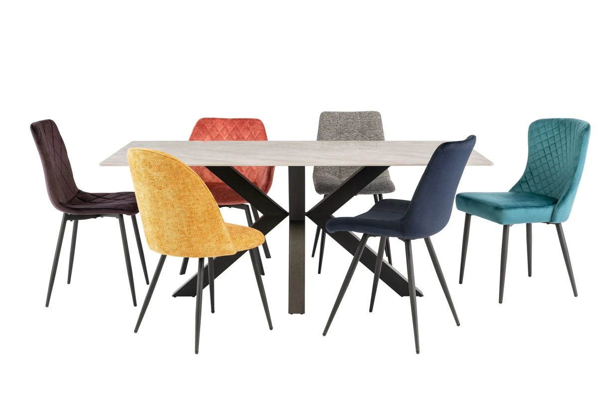 Modern dining table with black metal legs and six colorful fabric dining chairs