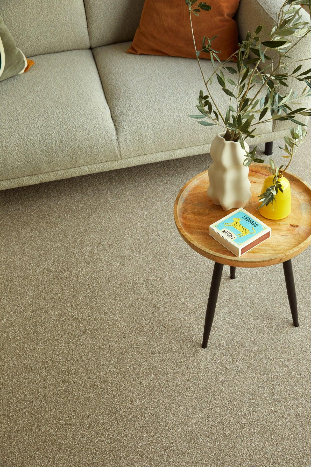 Beige carpet in living room styled with wooden table, vase, and greenery — cozy setting