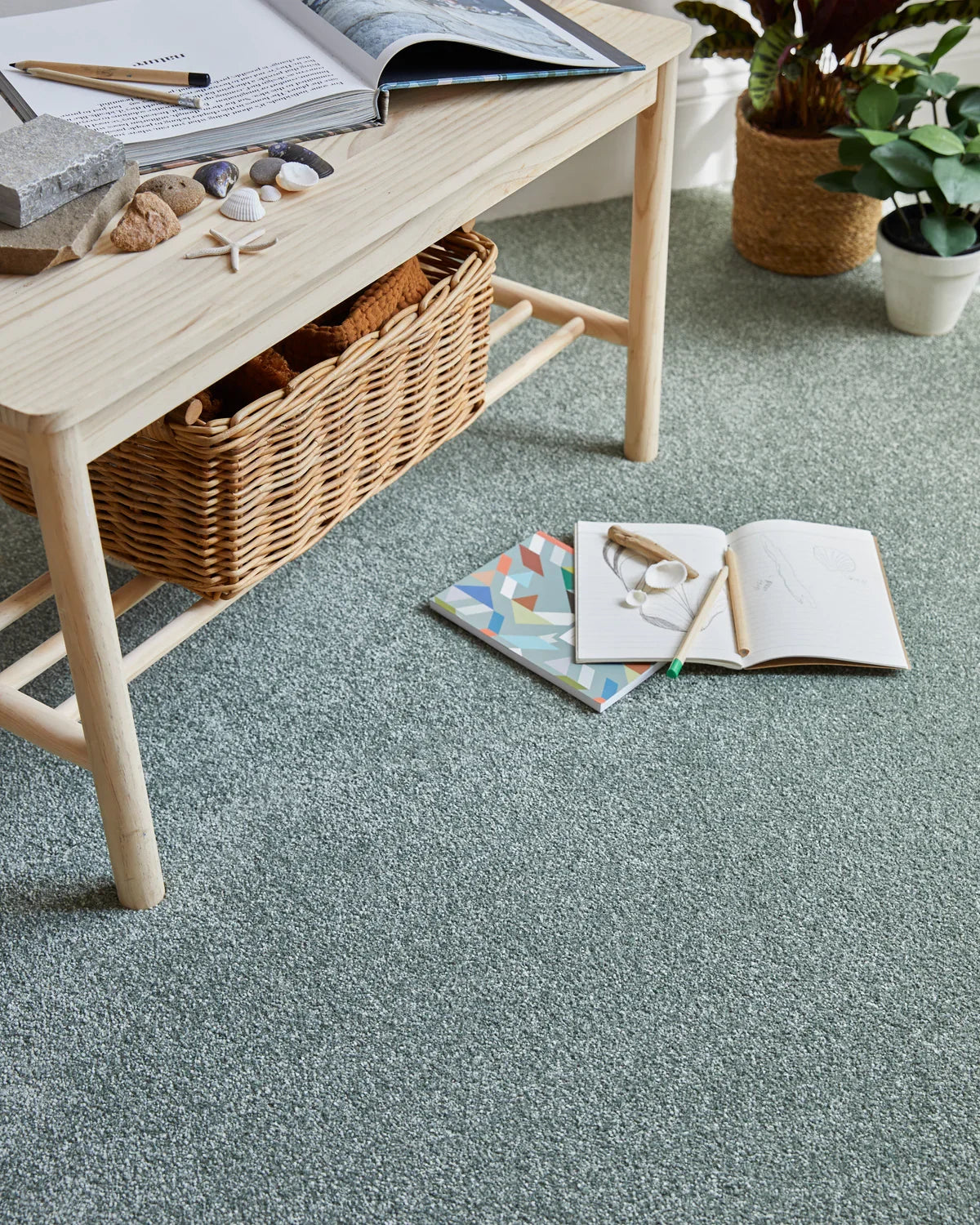 sage green saxony carpet in living room with wooden table, wicker basket, and houseplants