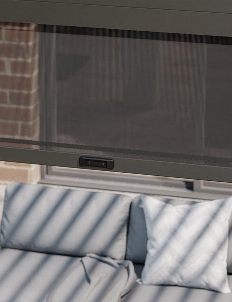 Mesh patio curtain with control panel over outdoor sofa and cushions
