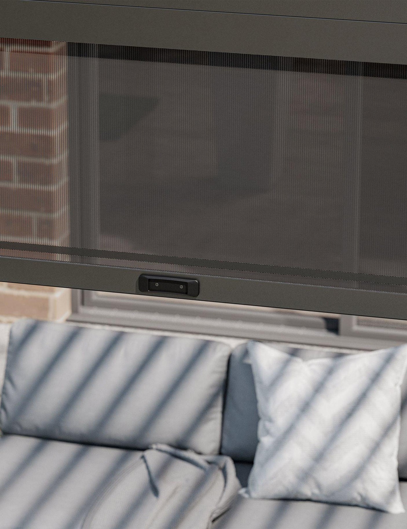 Mesh patio curtain with control panel over outdoor sofa and cushions
