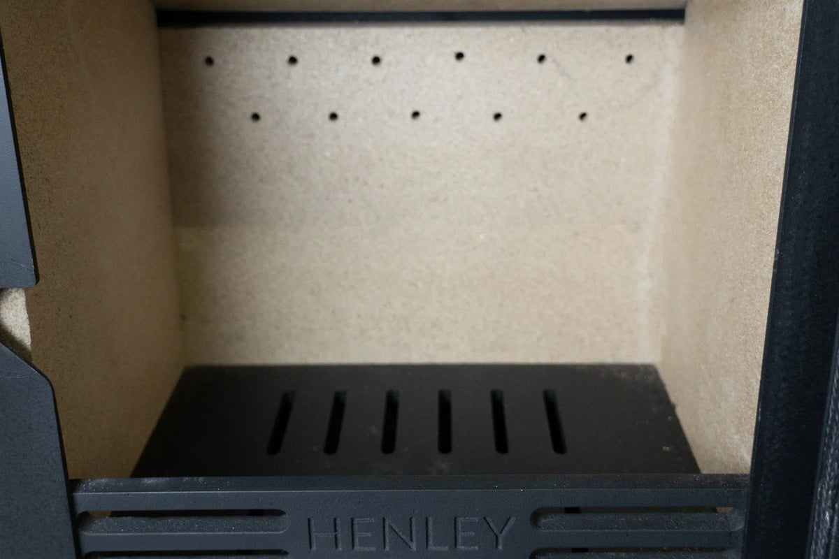 wood burning stove firebox with black grate and firebrick lining
