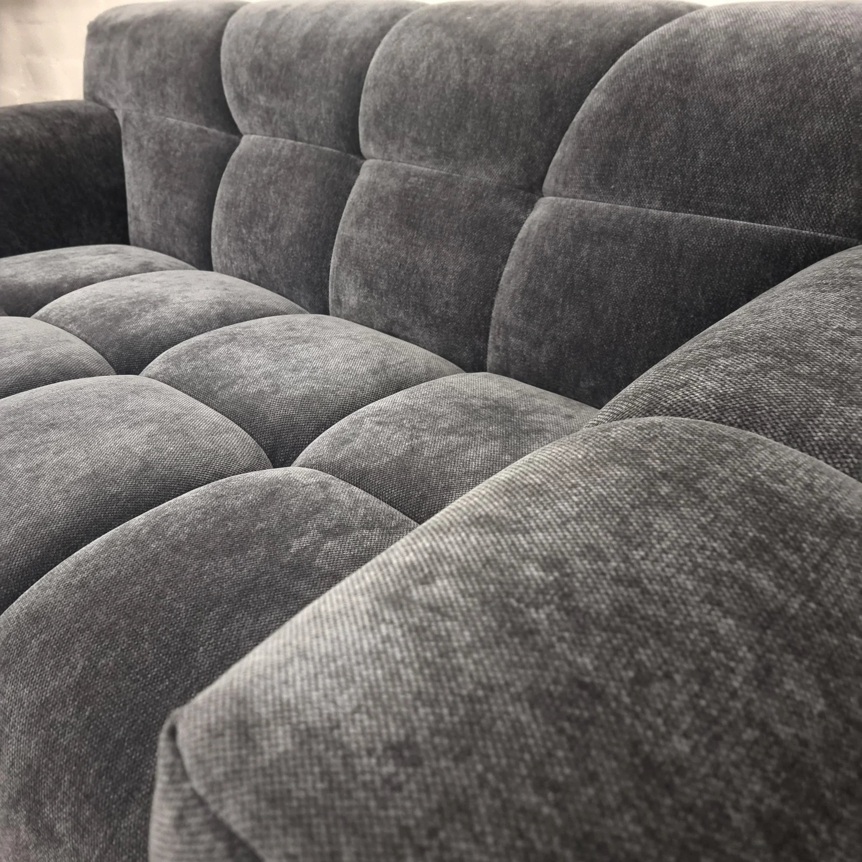 Close-up of grey fabric sofa upholstery with deep tufted cushions