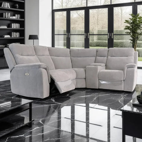 Gray sectional sofa in a modern living room with large windows and a plant.