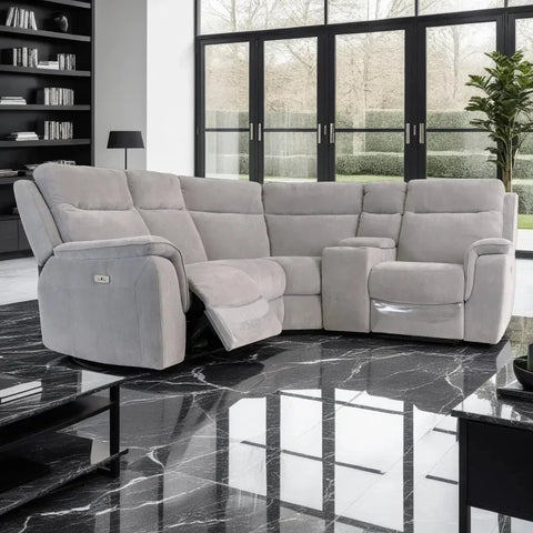 Gray sectional sofa in a modern living room with large windows and a plant.