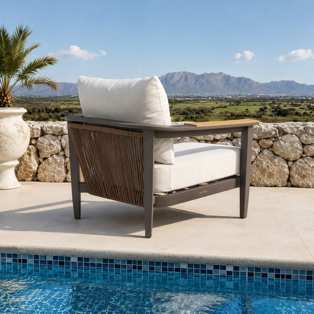 Cream fabric cushions on dark brown metal chair frame with woven rope sides near pool